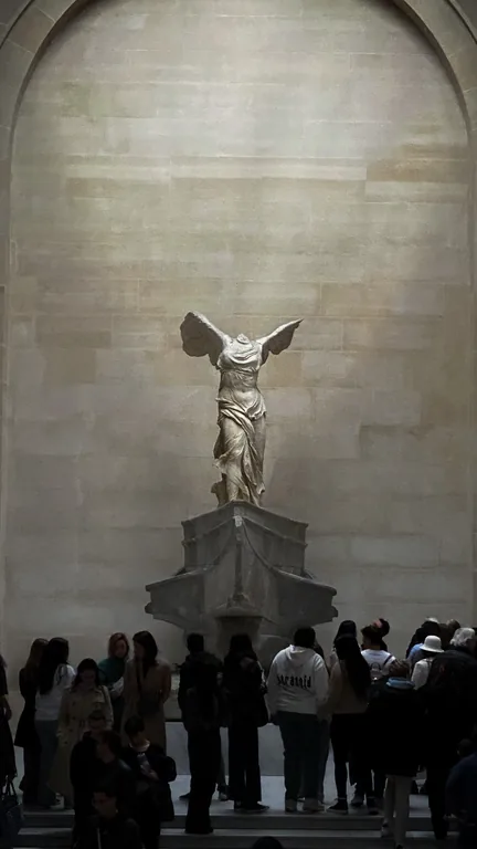 Statue ailée au sommet d’un escalier monumental.