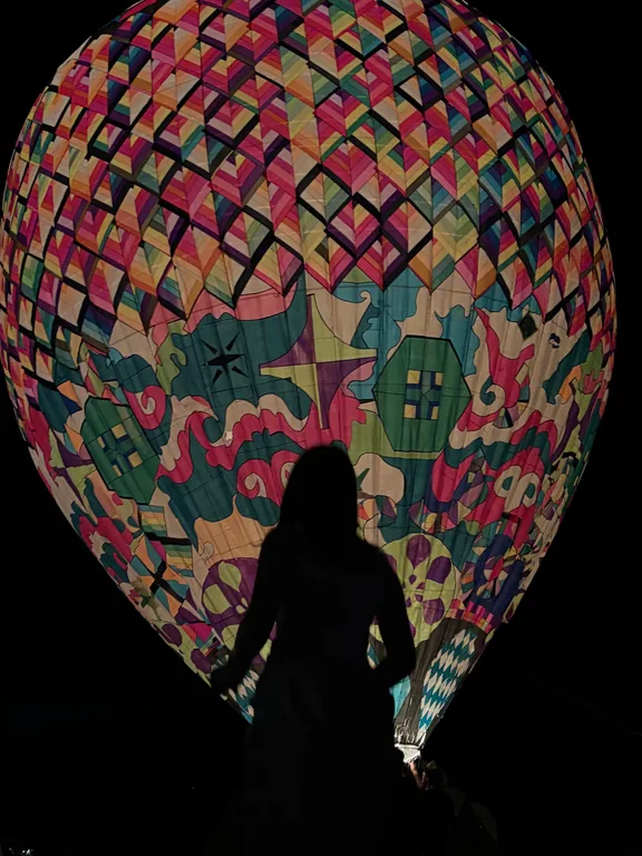 Silhouette devant une grande forme lumineuse aux motifs colorés.