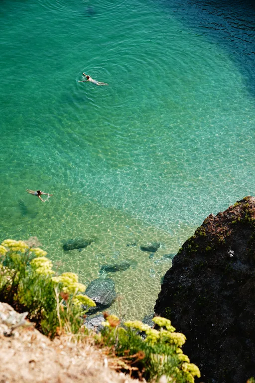 Eau turquoise et rochers vus depuis le bord d’une falaise.